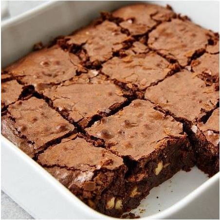 Un grand brownie coupé en quadrillé dans un plat à four blanc